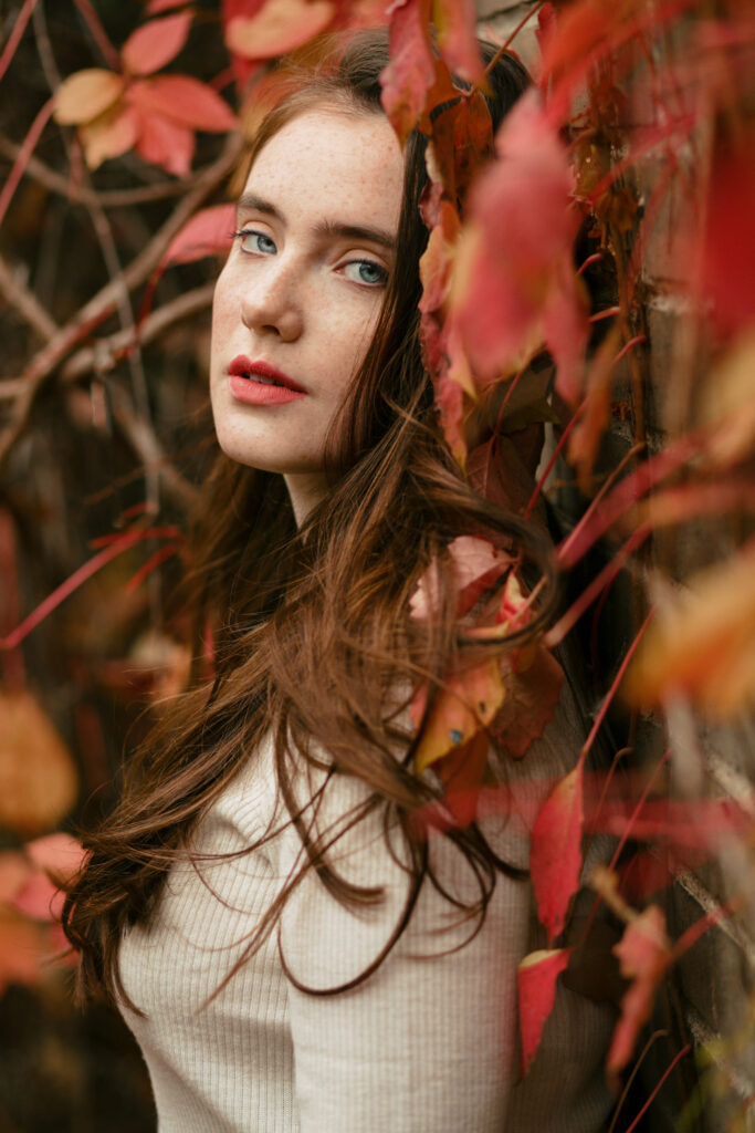 photo of red headed girl leaning on wall of red fall leaves for national love your red hair holiday
